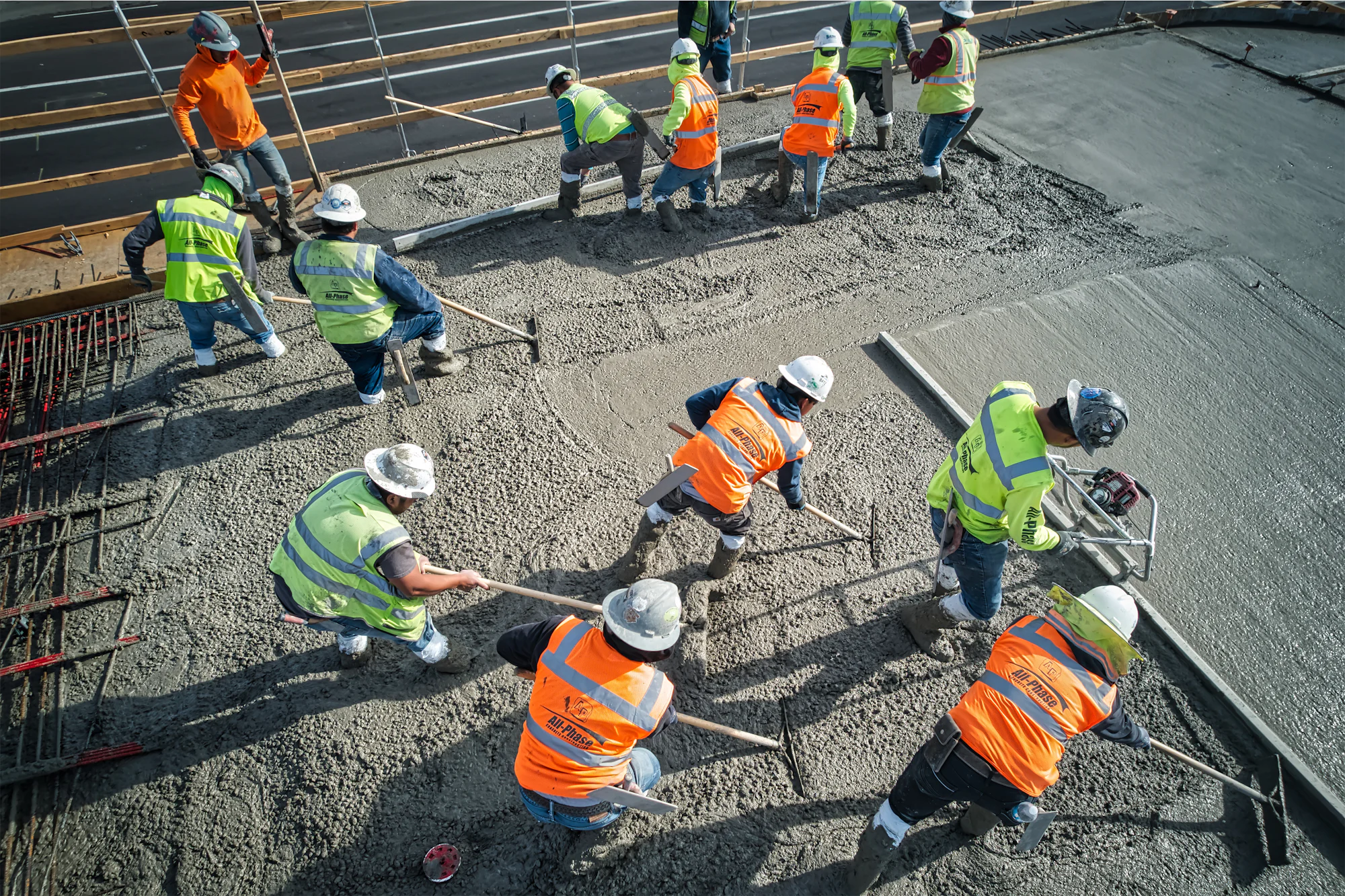 Şantiyede taze beton döşemeyi mastarla düzelten işçiler
